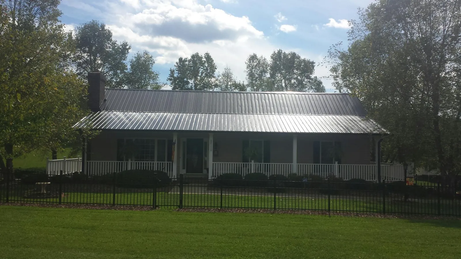 Gray metal roof on a brick ranch with a full width front porch — Gutter Guard Installation work by our crew in Magnolia